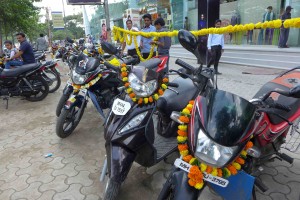 Motorcycles in front of the store decorated with garlands (most cars, trucks, and entrances to businesses are garlanded too). 